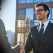 Business professionals shaking hands to discuss AI and cloud transformation with a Microsoft partner.